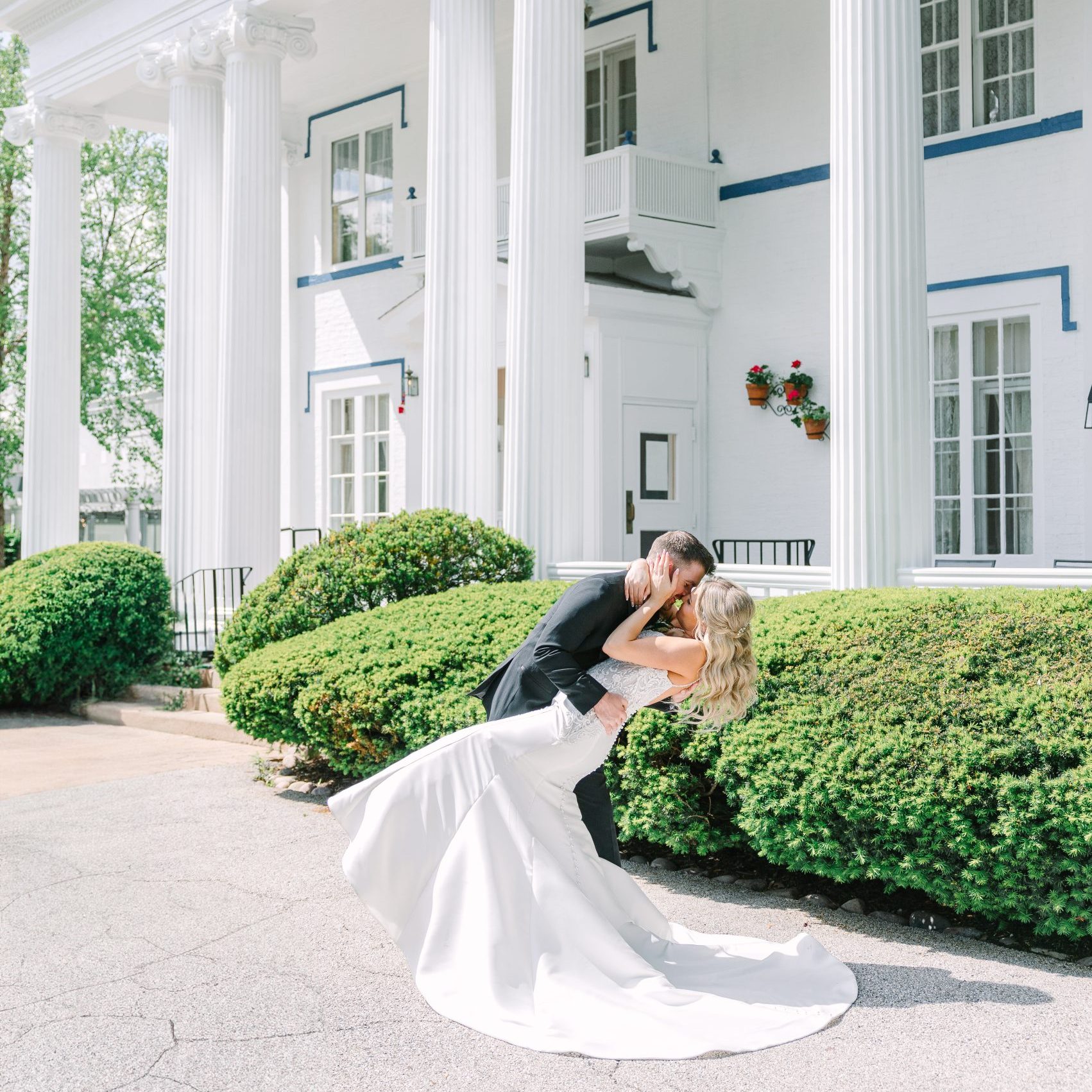 A couple dipping for a kiss beside the mansion