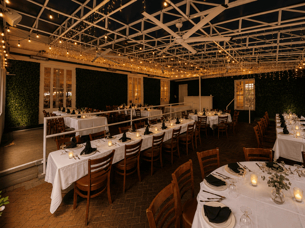The veranda at dusk, strung with lights above set tables